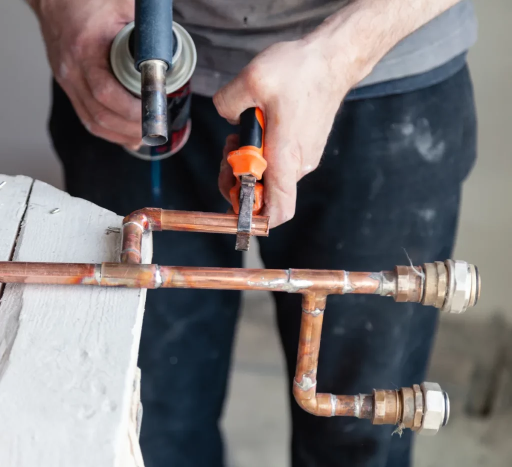 Plombier chauffagiste posant des tuyaux en cuivre à Paris, Île-de-France