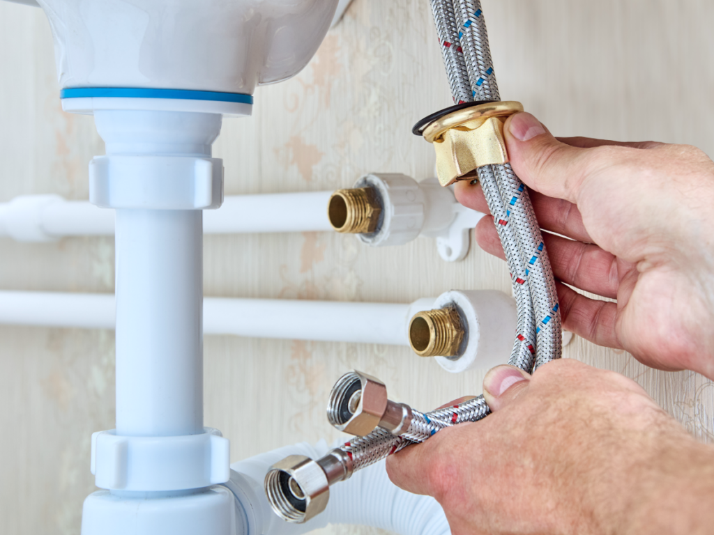 Plombier raccordant des tuyaux sous un évier à Paris, Île-de-France